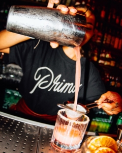 Bartender sirviendo un cóctel desde la coctelera en la barra de Primo, en el centro de Madrid