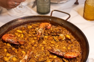 Grupo brindando con vino sobre una paella de marisco, restaurantes para grupos en Madrid
