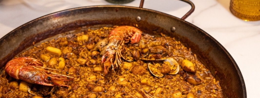 Grupo brindando con vino sobre una paella de marisco, restaurantes para grupos en Madrid